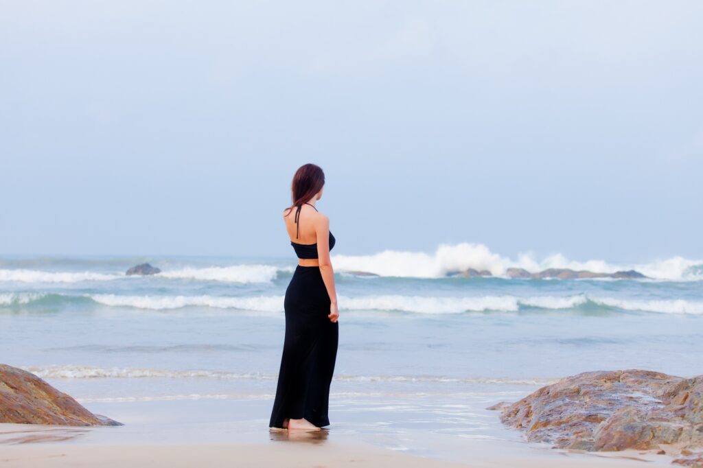 beautiful young woman standing on the sand coast in sunny Sri Lanka